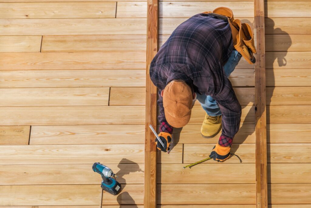 Top view of a man in work gear building a wooden deck.