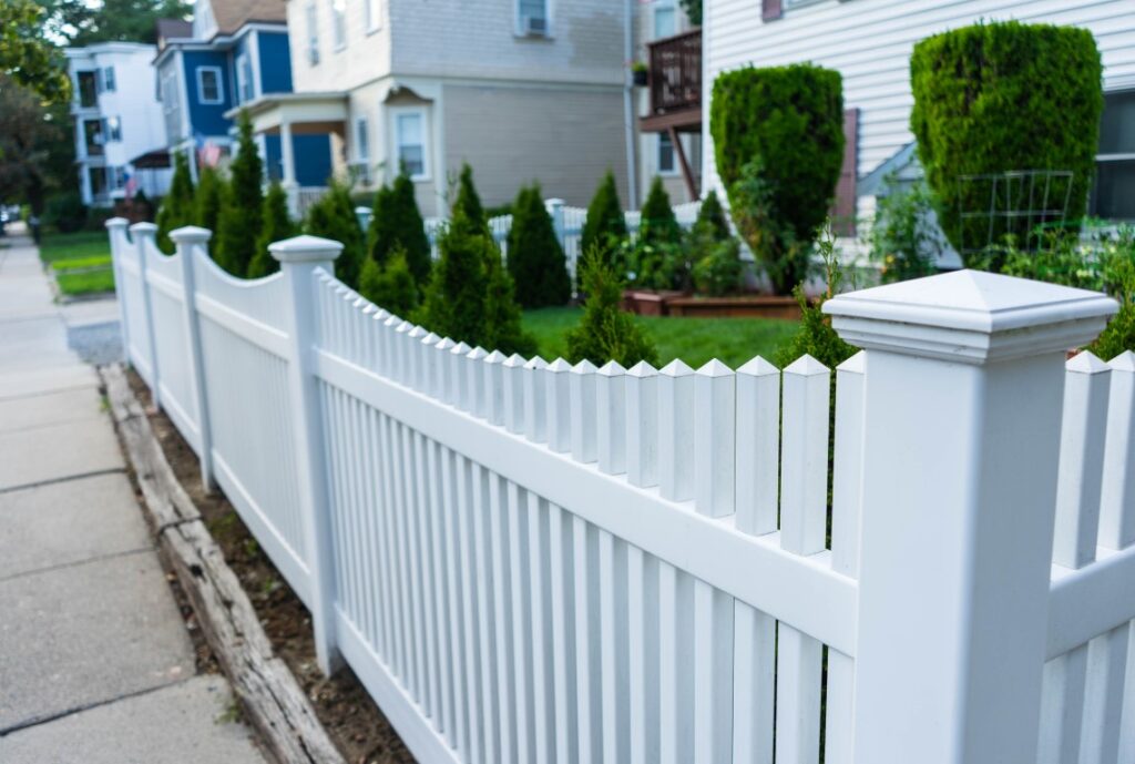 A white picket fence surrounding the yard of a house.